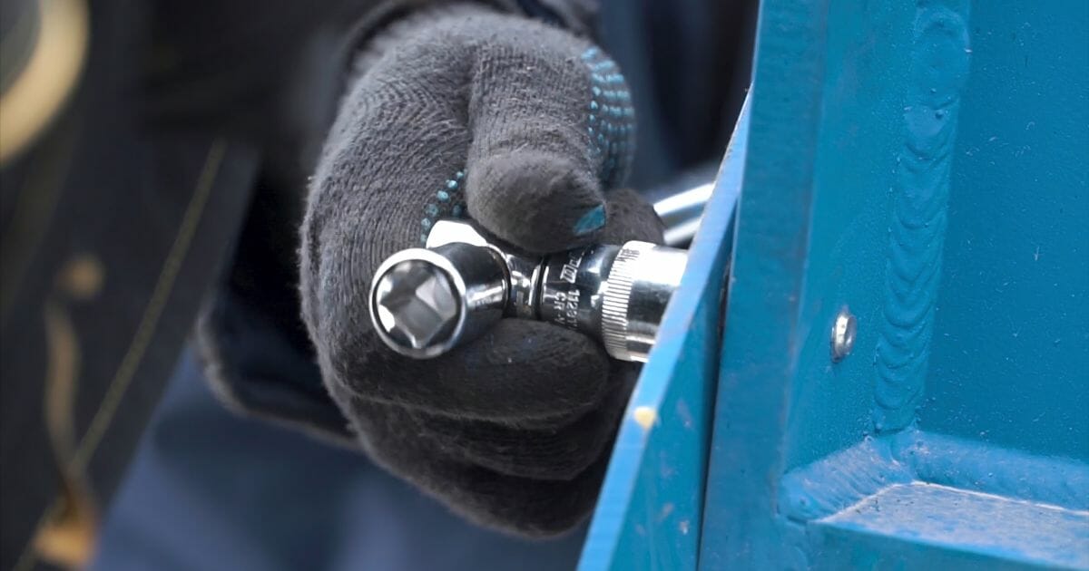 Close up for Man Hands in Protective Gloves Loosening the Bolt with a Wrench on the Metal Blue Structure. Clip. Dismantling of the Metal Construction.